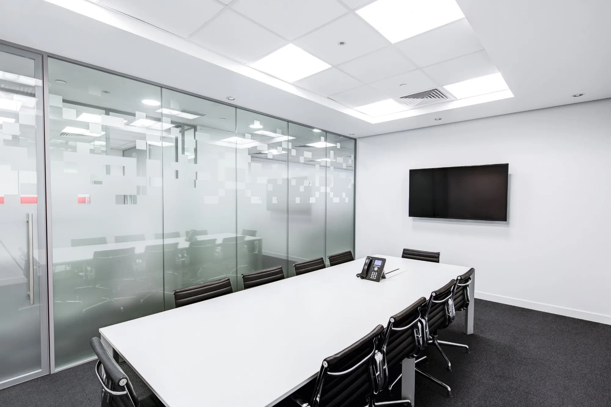 Modern office meeting room with glass walls, clean table surfaces, and professional finishes